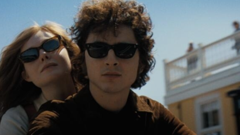 Elle Fanning (left) plays the character Sylvie Russo, based on Bob Dylan’s (Timothée Chalamet’s) one-time girlfriend Suze Rotolo, who was pictured <a rel=nofollow noopener noreferrer href=https://en.wikipedia.org/wiki/The_Freewheelin%27_Bob_Dylan target=_blank>clinging to Dylan’s arm</a> on the cover of the 1963 album <i>“Freewheelin’ Bob Dylan.”</i>