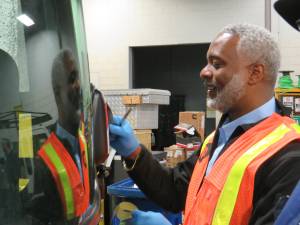 NYC Transit president Demetrius Crichlow, donning an orange safety vest at the Mother Hale Bus Depot, helped out on National Transit Employee Appreciation Day March 18, by changing a bus’s broken mirror, under the guidance of a Hale Bus Depot mechanic.