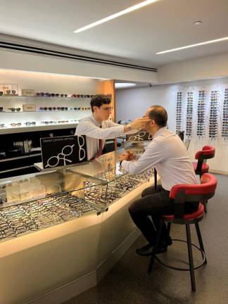 Jordan Stein, grandson of the company founder who started the firm inside Grand Central in 1924, fits a customer for eye glasses. He’s the third generation to be involved in the family business.