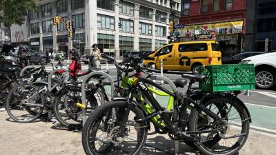 E-bikes parrked on 8th Avenue, between 37th and 38th street. If two bills recently passed in the NYS Assembly are passed by the New York State Senate and signed by Gov. Hochul, further e-bike safety regulations will be put in place, including a statewide ban on e-bikes driving on sidewalks.