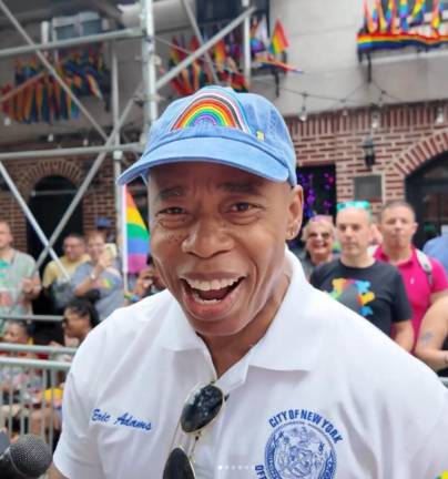 Ebullient Mayor Adams in a rainbow flag Pride hat.