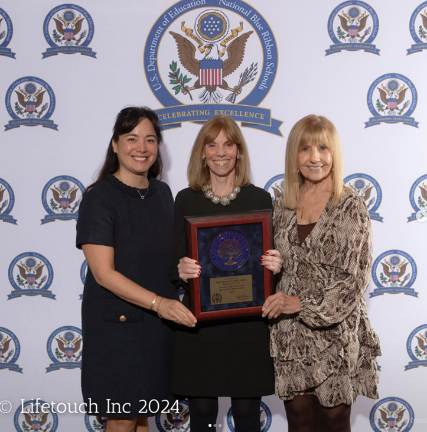 Principal Mark Larkin (center) proudly displays the school’s 2024 Blue Ribbon Award from the US Department of Education with her colleagues at the UES where she heads the pre-K through Eighth Grade School.