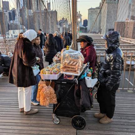 A bridge between two boroughs, and a cart selling fruit and churros. Dec. 8, 2024.