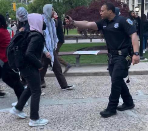 A CUNY campus police officer aims pepper spray at a protester’s face during a confrontation at City College, April 30, 2024. Photo: Luca GoldMansour/NYCity News Service