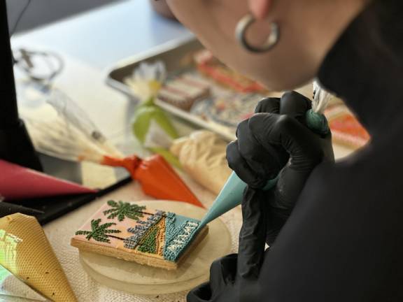 Abbey Kowalec puts the finishing touches on her latest creation. A batch of a dozen cookies can range in price from $150 to $250 and she has a waiting list.