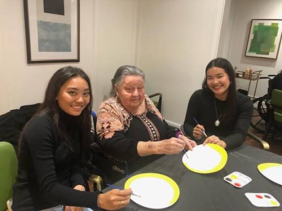 Volunteers Kaitlyn Sato and Sofia Balanay flank resident Janice Wolkenberg at Sunrise.