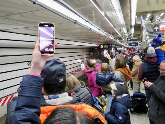 A nostalgia train gets photobombed by iPhones as it rumbles into the station at the 96th St. Second Avenue station a stop which did not exist when the R1/9 trains were the pride of the fleet. They were retired in 1977. Although the station was envisioned in the 1920s, it did not come to pass until 100 years laer.