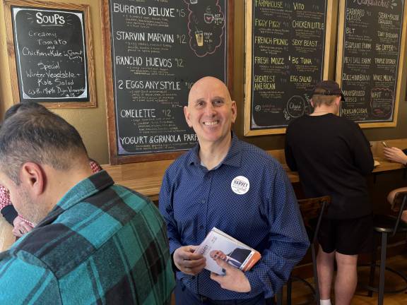 State Assemblymember Harvey Epstein gathers petitions in an East Village café on March 1.