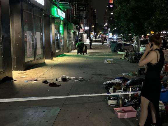A young woman was horrified to view the bloodstained sidewalk where a man was stabbed to death and two other injured on E. 14th St. on June 23. Photo: Keith J. Kelly