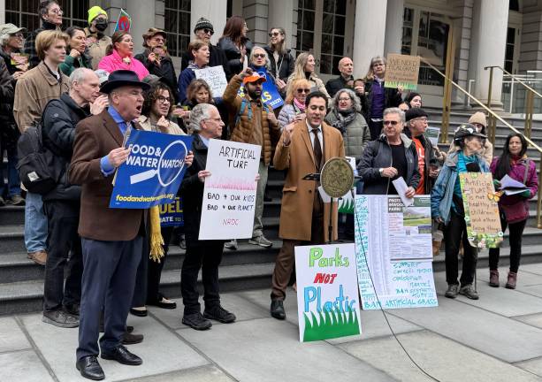 Council Member Christopher Marte, front row center, leads supporters in a chant against artificial turf in New York City parks. Marte has introduced a bill that seeks to end the further usage of synthetic turf, referred to as the “Touch Grass Bill.”