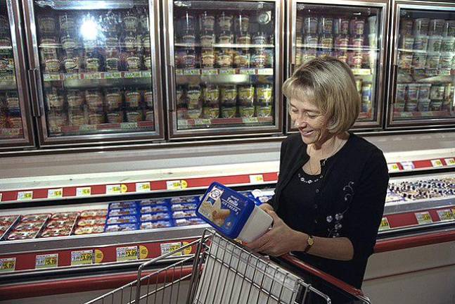 Wonder what she found? A woman shopper laughs as she checks the label on an ice cream container.