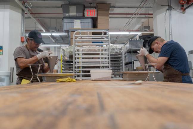 Asad Hana (pictured on the right) works alongside his colleague to create the brand's signature Nonpareils, which are small dollops of chocolate dropped onto a tray of colorful nonpareils to create bite-sized confections.