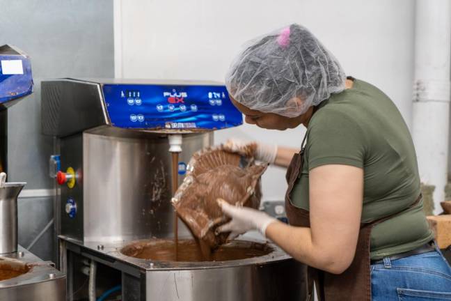 Damarys begins her chocolate making process by filling the turkey mold with a thin layer of chocolate. After which she dusts off the excess and repeats the first step.