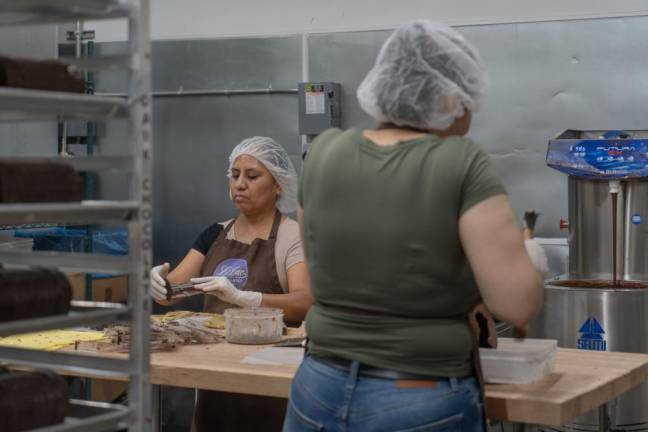 Damarys and Gicela work together on creating separate chocolate molds.